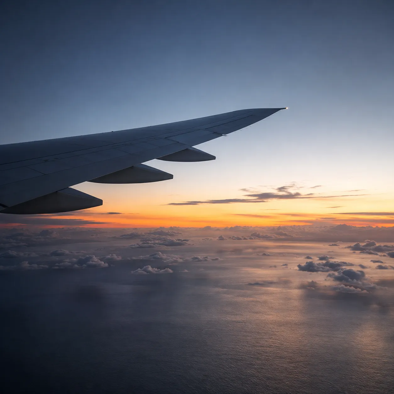 View of an aircraft wing above the clouds at dusk